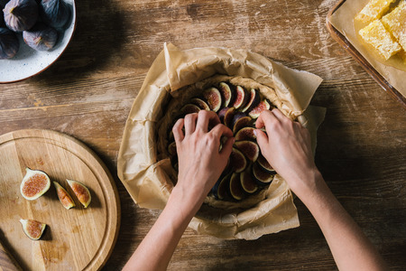 cropped shot of woman preparing delicious fig pie on wooden tableの写真素材