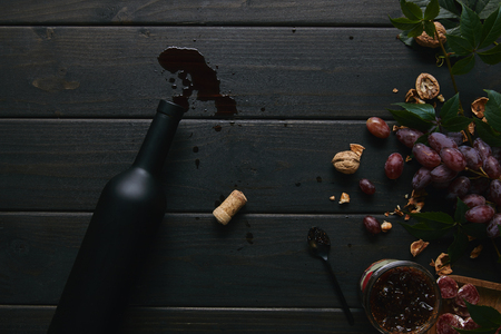 top view of wine bottle, cork and grapes with nuts on wooden surfaceの写真素材