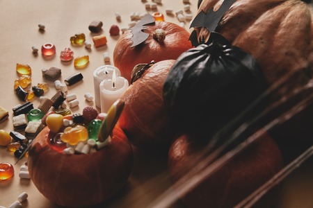 high angle view of halloween pumpkins, jelly candies and paper bats on table