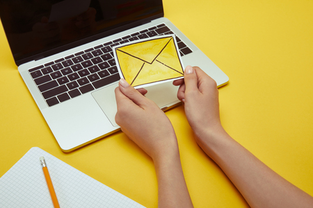 cropped image of woman holding envelope sign near laptopの写真素材