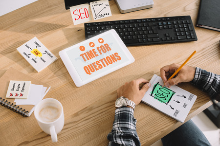 cropped shot of successful seo manager with tablet at workplace making notes in notepadの写真素材