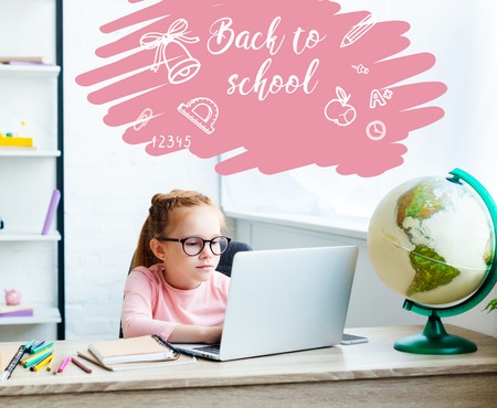 beautiful child in eyeglasses using laptop while studying at desk at home, with back to school letteringの写真素材