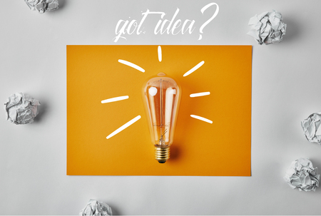 top view of incandescent lamp on blank yellow paper with got idea? lettering surrounded with...
