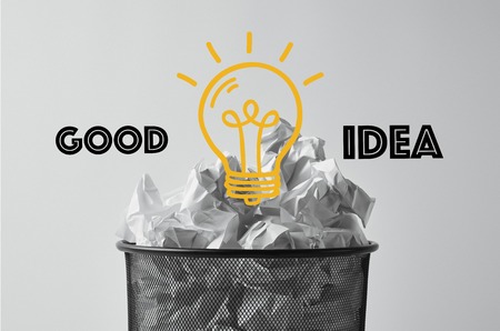 office trash bin with crumpled papers isolated on white with light bulb and good idea lettering