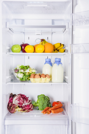 fruits, vegetables and milk with eggs in fridgeの写真素材
