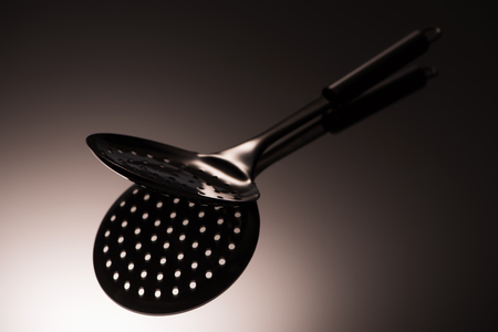 close-up view of single black colander reflected on greyの写真素材