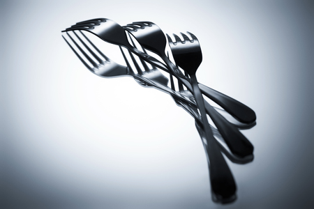 close-up view of set of shiny metal forks reflected on grey