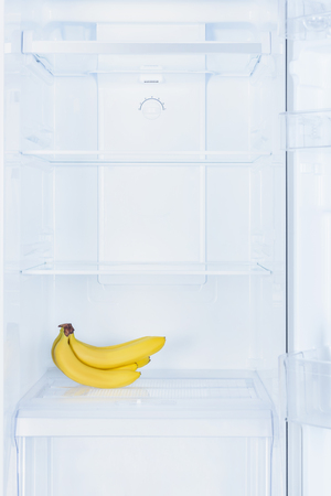 ripe appetizing bananas on shelf in fridgeの写真素材
