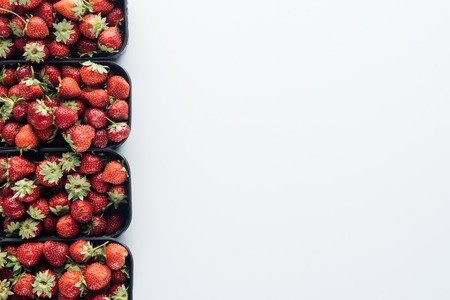 top view of row of containers with ripe strawberries on white tabletop with blank copy spaceの写真素材