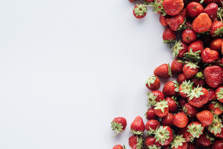 top view of pile of strawberries on white surface with blank copy spaceの写真素材