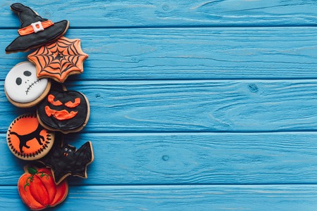 top view of spooky homemade halloween cookies placed in row on blue wooden backgroundの写真素材