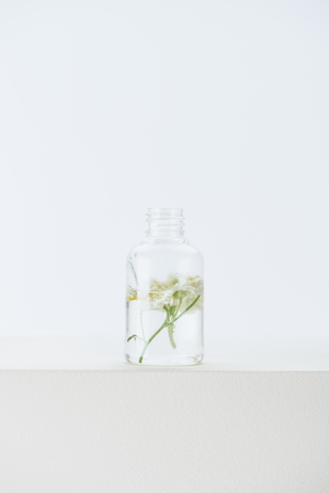 bottle of natural herbal essential oil with chamomile flowers on white surfaceの写真素材