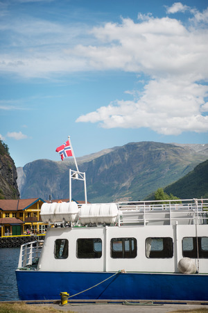 AURLANDSFJORD, FLAM, NORWAY - 27 JULY, 2018: boat with norway flag moored in harbour at Aurlandsfjord, Flam (Aurlandsfjorden), Norwayのeditorial素材