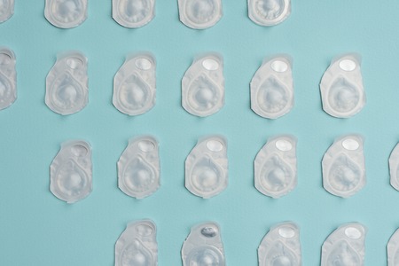 full frame of contact lenses in containers arranged on blue background