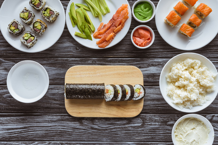 top view of delicious sushi rolls and ingredients on wooden tableの写真素材