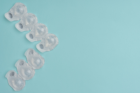 flat lay with contact lenses in white containers arranged on blue background