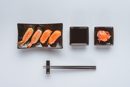 top view of gourmet sushi with salmon and shrimp, ginger and chopsticks isolated on whiteの写真素材
