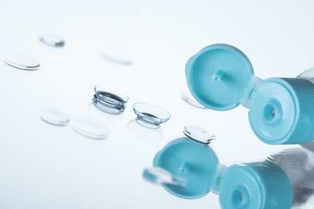 close up view of contact eye lenses and bottle with cleansing liquid on background with reflectionの写真素材