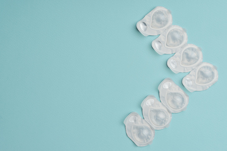flat lay with contact lenses in white containers arranged on blue backgroundの写真素材