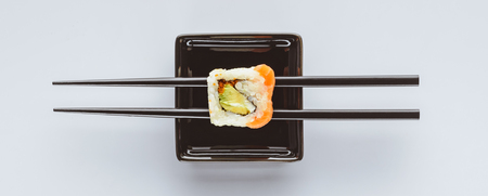 close-up view of tasty sushi and chopsticks isolated on white