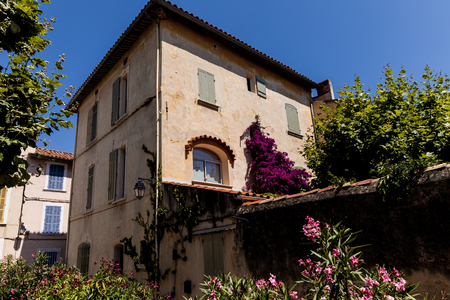 low angle view of beautiful traditional house with green vegetation and blooming flowers at sunny day, provence, franceの写真素材