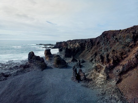 aerial view of rocky seashore with grey sand, djpalnssandur beach, iceland