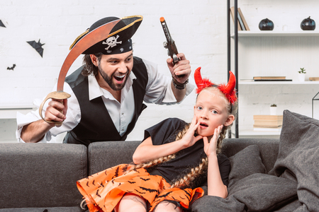 portrait of daughter and father in halloween costumes playing at homeの写真素材