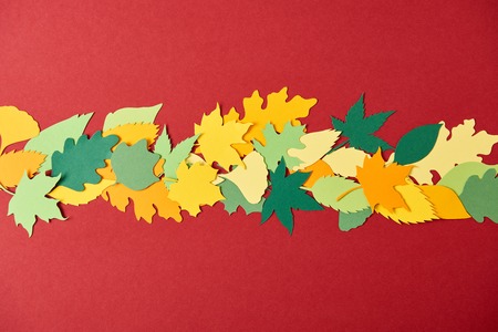 flat lay with colorful papercrafted leaves arrangement on red backgroundの写真素材