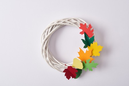 top view of handmade wreath with colorful paper foliage on white backdropの写真素材