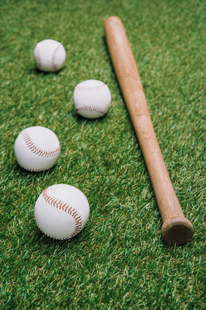 close up view of baseball bat and balls arranged on green lawnの写真素材