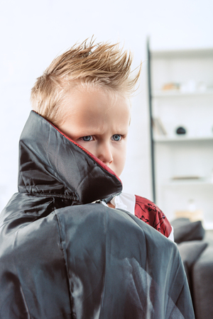 portrait of little grumpy boy in vampire halloween costume at homeの写真素材