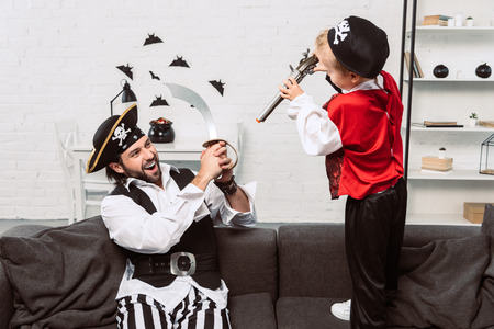 father and son in pirate costumes playing at home, halloween holiday conceptの写真素材
