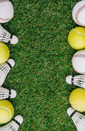 top view of arrangement of badminton shuttlecocks, tennis and baseball balls on green lawnの写真素材