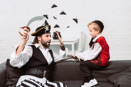 father and son in pirate costumes playing at home, halloween holiday conceptの写真素材