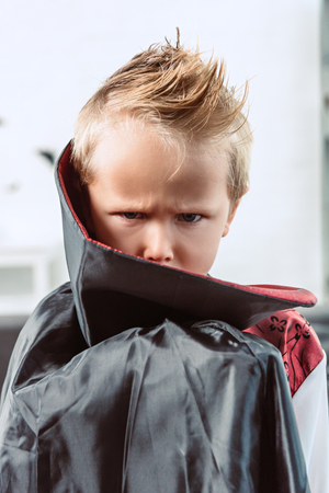 portrait of little boy in vampire halloween costume looking at camera at homeの写真素材