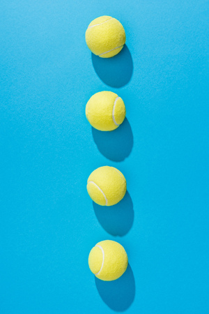 top view of arranged tennis balls on blue backgroundの写真素材