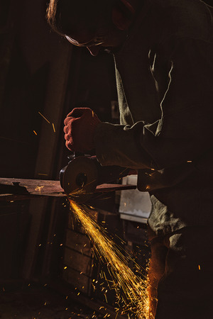 male worker in protective googles working with circular saw at factoryの写真素材