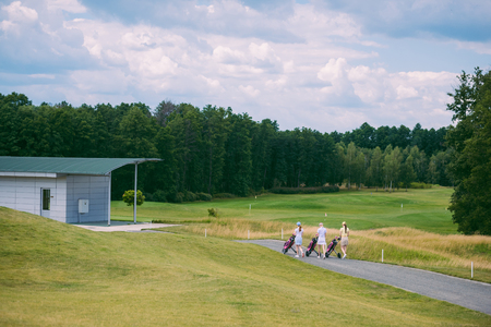 female golfers with golf gear walking at golf course on summer dayの写真素材