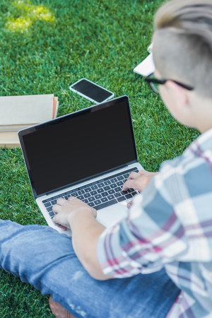 cropped shot of teenager using laptop with blank screen while studying in parkの写真素材