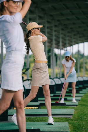 selective focus of women in caps playing golf at golf courseの写真素材