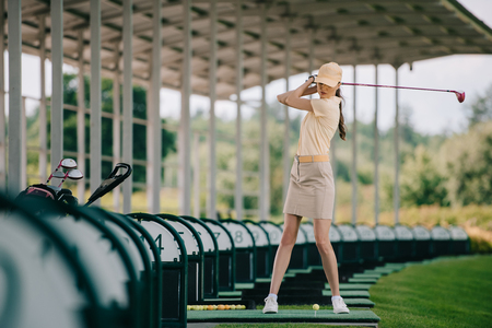 woman in yellow cap and polo playing golf at golf courseの写真素材
