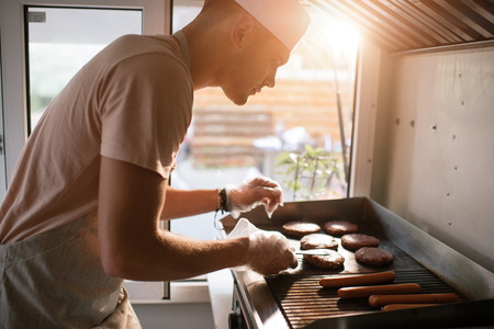 side view of chef preparing meat for burgers in food truckの写真素材