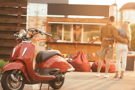 back view of couple standing near food truck with scooter on foregroundの写真素材
