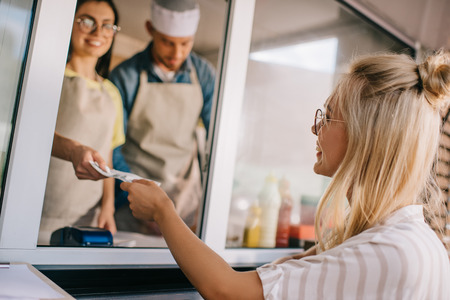 smiling young woman paying in food truckの写真素材