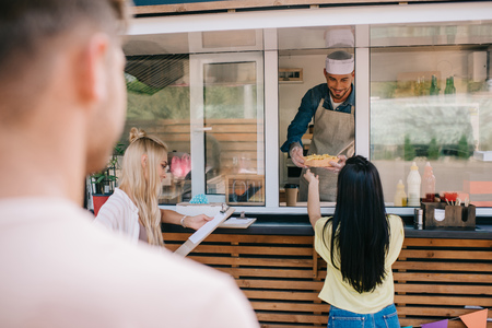 selective focus of young people buying fast food at food truckの写真素材