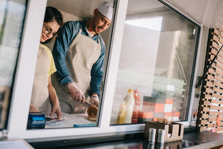 smiling young male and female workers working together at food truck