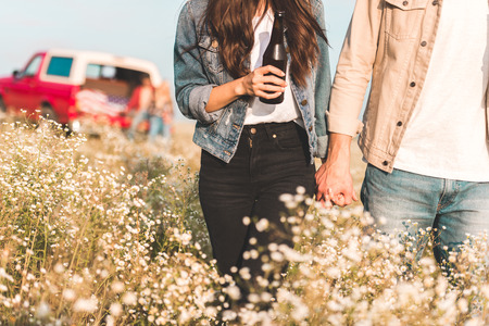 cropped shot of couple holding hands and walking by flower fieldの写真素材