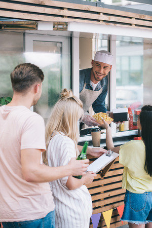 smiling chef giving french fries to girl from food truckの写真素材