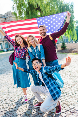 Smiling multicultural students with american flag in parkの写真素材