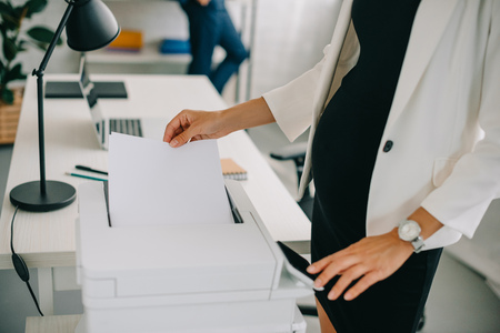 partial view of pregnant businesswoman using printer in officeの写真素材